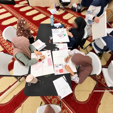 Girls making collages around a table, seen from above