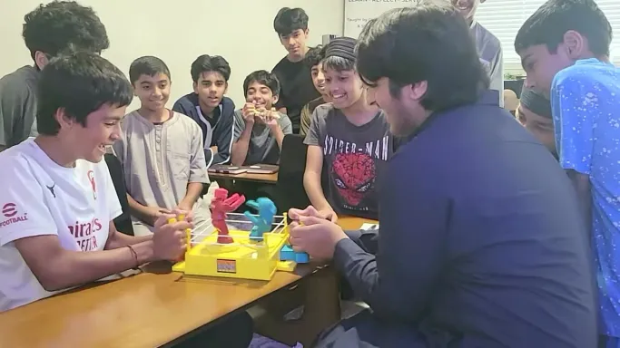 Teen boys crowding around a robot boxing game