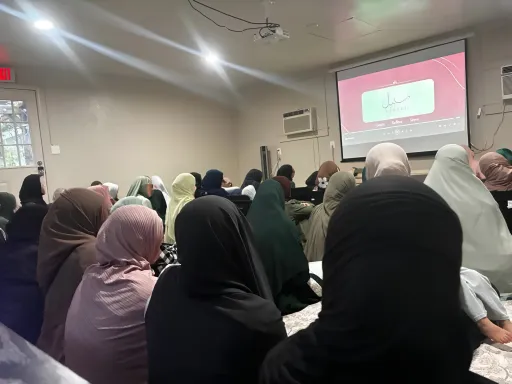 A full room of women seen from behind, watching a slide with the Sabeel logo