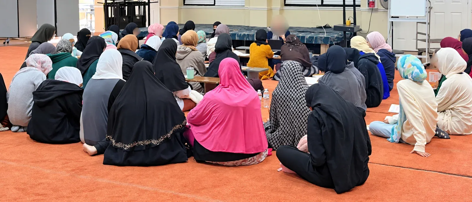 Girls seated in a circle on the carpet around their teacher